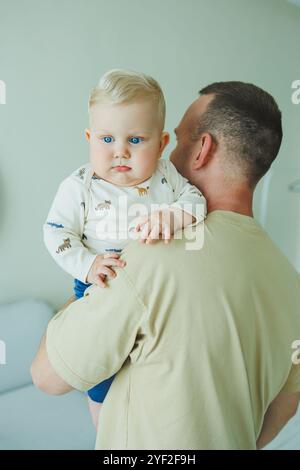 Der junge lächelnde Vater spielt mit seinem neugeborenen Sohn. Dad und kleiner Sohn. Stockfoto