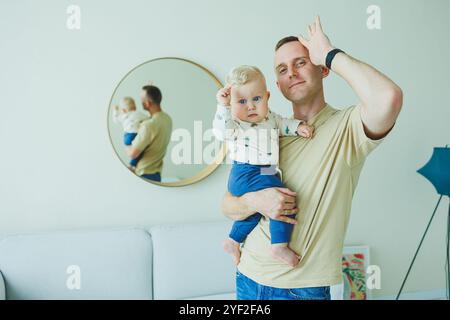 Der junge lächelnde Vater spielt mit seinem neugeborenen Sohn. Dad und kleiner Sohn. Stockfoto