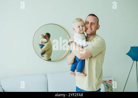 Der junge lächelnde Vater spielt mit seinem neugeborenen Sohn. Dad und kleiner Sohn. Stockfoto