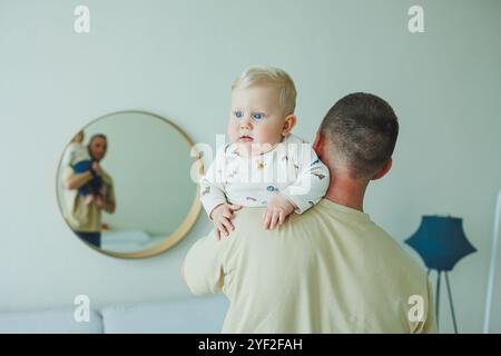 Der junge lächelnde Vater spielt mit seinem neugeborenen Sohn. Dad und kleiner Sohn. Stockfoto