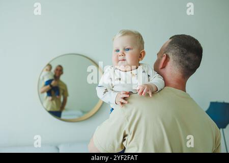 Der junge lächelnde Vater spielt mit seinem neugeborenen Sohn. Dad und kleiner Sohn. Stockfoto