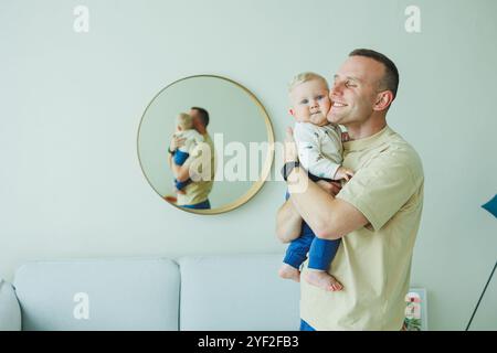 Der junge lächelnde Vater spielt mit seinem neugeborenen Sohn. Dad und kleiner Sohn. Stockfoto