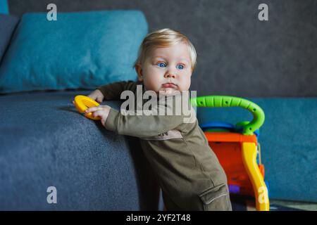 Erste Schritte des Babys. Glückliches Familienkind-Traumkonzept. Vater bringt der Tochter bei, dass sie vor dem Fenster erste Schritte im Lifestyle zu Hause macht. Vatertag Stockfoto