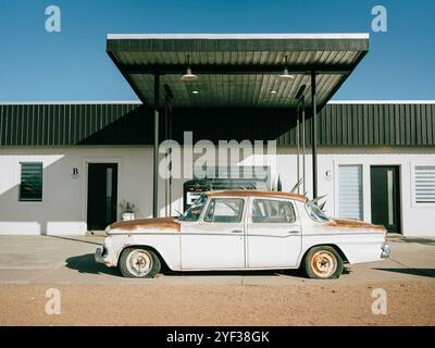 Ein altes rostiges Auto steht vor einem modernen Gebäude mit schwarzen Markisen in Marfa, Texas. Stockfoto