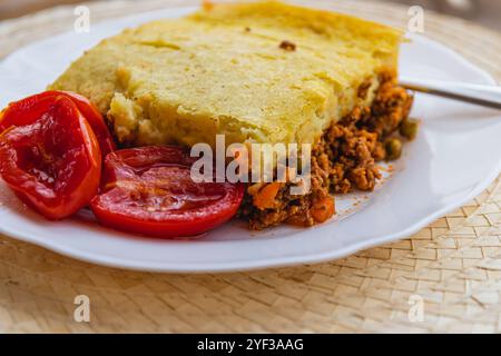 Frisch zubereiteter Hirtenkuchen mit eingelegten Tomaten auf einem weißen Teller Stockfoto