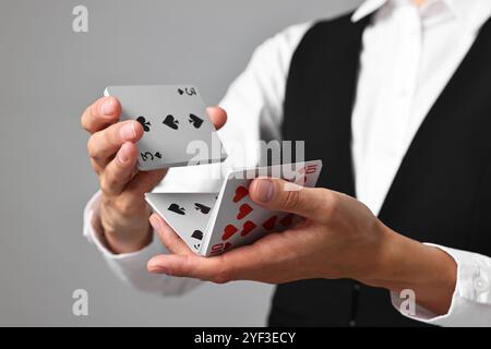 Professioneller Croupier, der Karten auf grauem Hintergrund mischt, Nahaufnahme Stockfoto