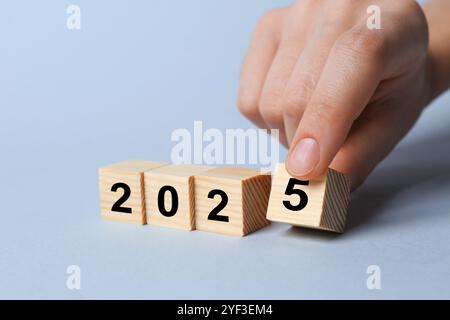 Neujahr 2025. Frau, die Holzwürfel mit Nummer 5 auf hellgrauem Hintergrund legt, Nahaufnahme Stockfoto