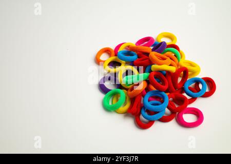 Ein Haufen bunter elastischer Haargummis, die auf einer weißen Oberfläche verstreut sind Stockfoto