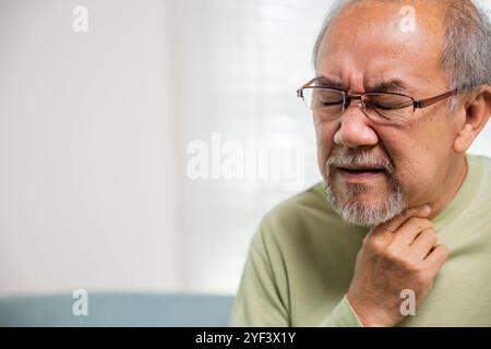 Seniorenmann im Ruhestand, der Schmerzen spürt, Hände, die den Hals halten, und Reizungen im Hals Stockfoto