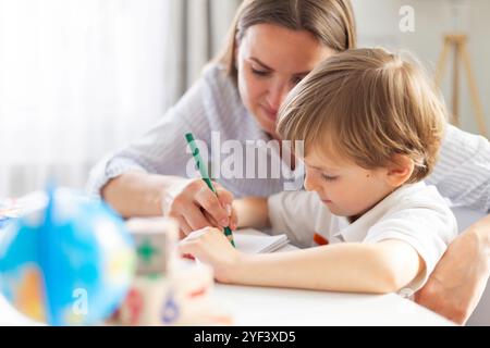 Mutter hilft dem Kind beim Schreiben Stockfoto