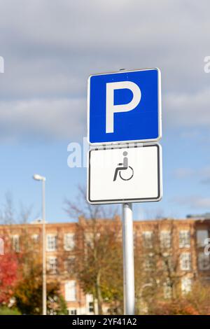 Ein blaues Parkschild, das auf Behindertenparkplätze hinweist. Das Schild zeigt ein Rollstuhlsymbol auf weißem Hintergrund, das den Zugang betont Stockfoto