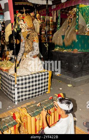 Ein Junge, der Rindik bei Kuningan Ceremony spielt, Rangda und Barong Landung Puppen, Pura Gunung Sari Tempel, Denpasar, Bali, Indonesien, Asien Stockfoto