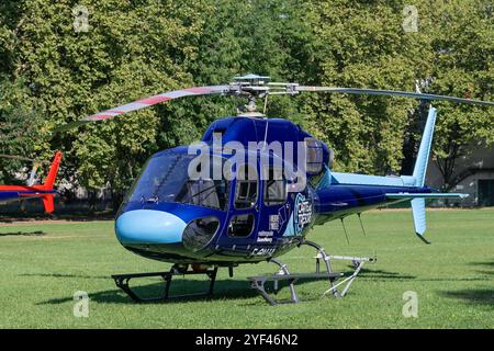 Nancy, Frankreich - Blick auf einen Hubschrauber Eurocopter AS355 Ecureuil 2 landete in einem öffentlichen Stadtpark mit Bäumen im Hintergrund. Stockfoto