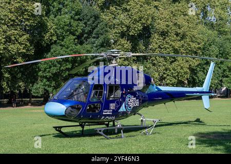 Nancy, Frankreich - Blick auf einen Hubschrauber Eurocopter AS355 Ecureuil 2 landete in einem öffentlichen Stadtpark mit Bäumen im Hintergrund. Stockfoto