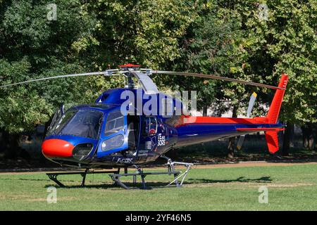 Nancy, Frankreich - Blick auf einen Hubschrauber Eurocopter AS355 Ecureuil 2 landete in einem öffentlichen Stadtpark mit Bäumen im Hintergrund. Stockfoto