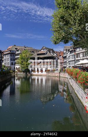 Straßburg, Frankreich - Blick auf das Tanner's Quarter mit farbigen Fachwerkhäusern und dem Fluss Ill und Reflexionen auf dem Wasser. Stockfoto