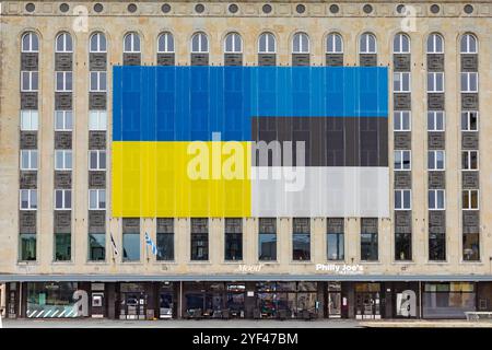 Tallinn, Estland - 27. Oktober 2024: Große estnische Flagge an der Fassade eines alten Bürogebäudes. Stockfoto