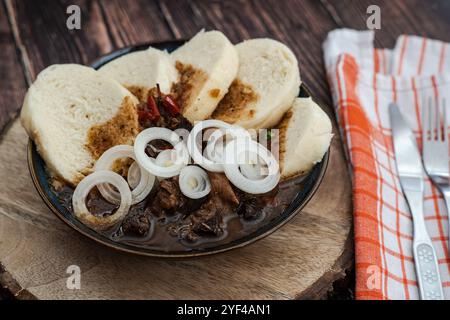 Die Szene zeigt ein traditionelles tschechisches Rindergulasch, serviert mit Brotknödeln und Zwiebeln. Dieses klassische Gericht im Pub-Stil wird in einem rustikalen Dinin serviert Stockfoto