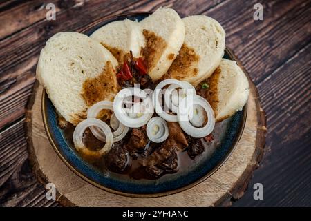 Die Szene zeigt ein traditionelles tschechisches Rindergulasch, serviert mit Brotknödeln und Zwiebeln. Dieses klassische Gericht im Pub-Stil wird in einem rustikalen Dinin serviert Stockfoto