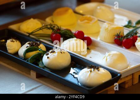 Frischer Burrata-Käse mit Trüffel und Kirschtomaten garniert auf eleganten Serviertabletts Stockfoto