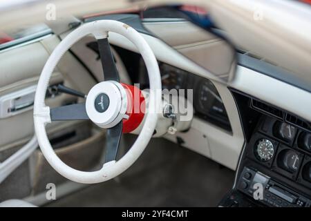 Oldtimer-Innenraum mit einzigartigem weißem Lenkrad, klassischem Armaturenbrett und Retro-Anzeigen, die zeitloses Automobildesign und nostalgischen Charme zeigen. Stockfoto