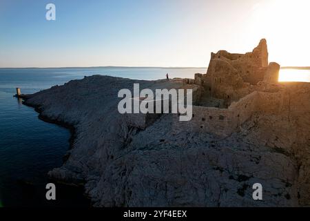 Touristen genießen den Sonnenuntergang an den Ruinen einer antiken Festung Fortica auf der Insel Pag in Dalmatien, Kroatien Stockfoto