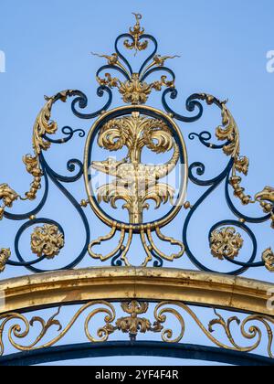 Blick auf altes goldenes gusseisernes Dekor mit Krokodil und Palme - Wappen der Stadt - am Jardins de la Fontaine Eingangstor, Nîmes, Frankreich Stockfoto