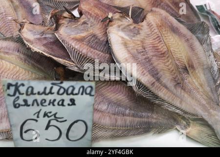 STADT PETROPAVLOVSK, HALBINSEL KAMTSCHATKA, RUSSISCHER FERNOST, 20. MAI 2018: Nahaufnahme von getrockneten gesalzenen Plattfischen mit Preis auf dem Fischmarkt. Stockfoto