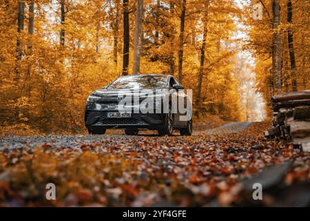 Auto durch Herbstwald mit Orangenblättern auf Schotterstraße, Elektroauto, VW ID 5, Gechingen, Schwarzwald, Deutschland, Europa Stockfoto