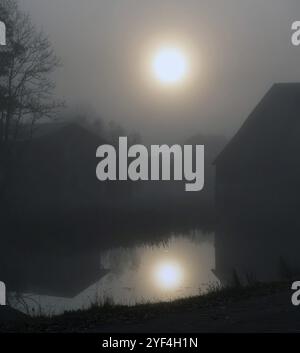 Mogen Sonne am nebeligen Morgen spiegelt sich in einem Dorfteich, Othenstorf, Mecklenburg-Vorpommern, Deutschland, Europa Stockfoto