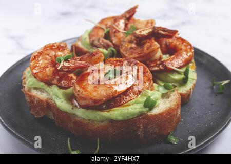 Sandwiches mit Avocado und karamelisierten Garnelen, Micro-Greens, Frühstück, auf einem Teller, Blick von oben, hausgemacht, keine Leute Stockfoto