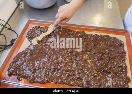 Nahaufnahme einer handaufreibenden Schokolade auf einer Backmatte mit Spachtel, Burch Schokolade Production, Haselstaller Hof, Gechingen, Deutschland, Europa Stockfoto