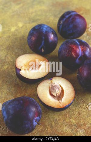 Pflaumen verstreut auf dem Tisch, frisch, Blick von oben, gelb-orange Hintergrund, keine Leute Stockfoto