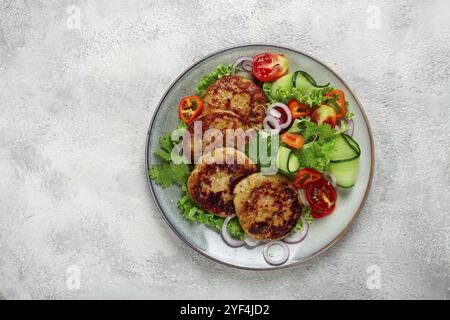 Gebratene Hähnchenkoteletts, gehacktes Hähnchen, mit Gemüse, auf Grau, mit Gemüsesalat, Aussicht von oben, hausgemacht, keine Leute Stockfoto