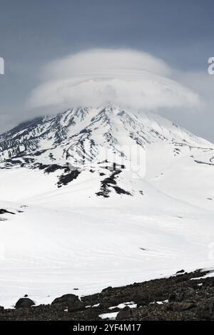 Winterliche Berglandschaft von Kamtschatka: Wunderschöner Blick auf den Korjakski-Vulkan (Korjakskaya Sopka) und Wolken, die die Spitze des aktiven Vulkans umhüllen. K Stockfoto