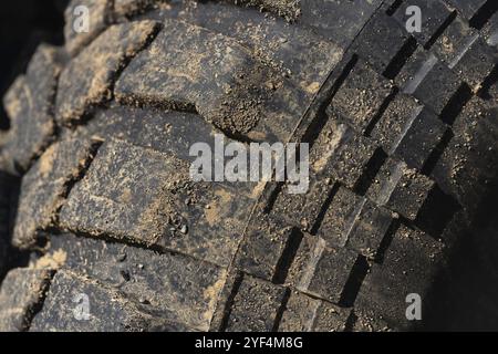 Alter gebrauchter Gummireifen mit verschleißfestem Profil. Nahaufnahme eines schwarzen, schlammigen Geländebereifens bei 4x4-Fahrzeugen mit anhaftendem Schmutz danach Stockfoto