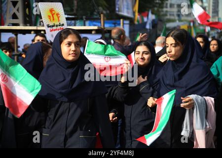 Teheran, Iran. November 2024. Iranische verschleierte Schulmädchen schwenken die iranische Flagge während einer Anti-US-Kundgebung zum 45. Jahrestag der Übernahme durch die US-Botschaft vor dem ehemaligen Botschaftsgebäude in Teheran. Am 4. November 1979 übernahmen iranische Studenten die US-Botschaft in Teheran und hielten über 50 amerikanische Diplomaten und Wärter 444 Tage lang als Geiseln. Diese Aktion folgte der Entscheidung der USA, dem entlassenen Schah aus dem Iran die medizinische Behandlung in Amerika zu erlauben. Vor kurzem, am 2. November, warnte der Oberste Führer Ayatollah Ali Khamenei vor einer ernsten Reaktion auf die USA und Israel nach der jüngsten israelischen Mission Stockfoto