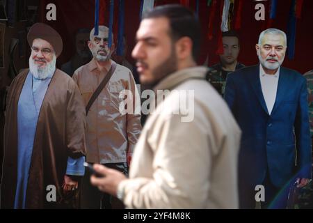 Teheran, Iran. November 2024. Ein iranischer Mann geht an den Maquetten des getöteten Leiters des Hamas-Politbüros, Ismail Haniyeh (R), des verstorbenen Anführers der militanten Hisbollah-Gruppe im Libanon, Hassan Nasrallah (L), und des getöteten Vorsitzenden des Hamas-Politbüros, Yahya Sinwar (2L) während einer Anti-US-Kundgebung zum 45. Jahrestag der Übernahme der US-Botschaft vor dem ehemaligen Botschaftsgebäude in Teheran. Am 4. November 1979 übernahmen iranische Studenten die US-Botschaft in Teheran und hielten über 50 amerikanische Diplomaten und Wärter 444 Tage lang als Geiseln. Diese Aktion folgte der US-Entscheidung Stockfoto