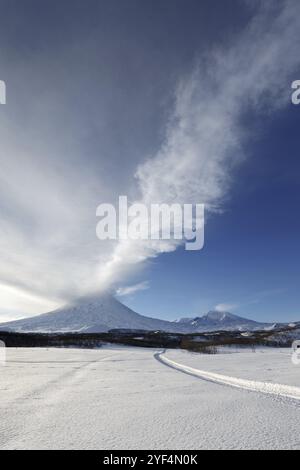 Malerische winterliche Landschaft der Halbinsel Kamtschatka: Abendlicher Blick auf den aktiven Klyutschevskoy-Vulkan (Klyuchevskaya Sopka), Emission aus dem Krater Stockfoto