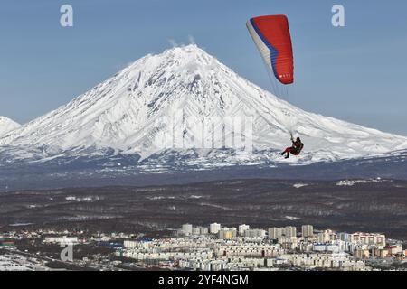 PETROPAVLOVSK-KAMTSCHATSKI, KAMTSCHATKA, RUSSLAND, 21. NOVEMBER 2014: Gleitschirmfliegen über Petropavlovsk-Kamtschatski-Stadt auf dem Hintergrund des aktiven K Stockfoto