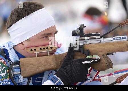 Nahaufnahme des sportlichen Biathleten zielt auf Gewehrschießen in Bauchlage. Biathlet Andrey Krutov auf dem Schießstand. Regionaler Jugendbiathlonwettbewerb Stockfoto