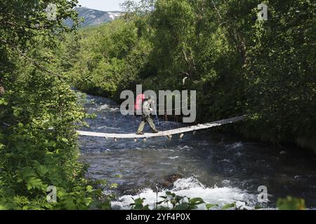 KAMTSCHATKA HALBINSEL, RUSSLAND, 11. JUL 2014: Sommerwandern auf Kamtschatka, touristische Frau und Reisende mit Rucksack hinter den Schultern, die den Berg überquert Stockfoto
