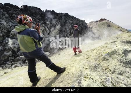 AVACHA VULKAN, KAMTSCHATKA HALBINSEL, RUSSISCHER FERNOST, 7. August 2014: Zwei junge Frauen fotografiert auf Smartphone auf dem Hintergrund von Schwefel fumaro Stockfoto