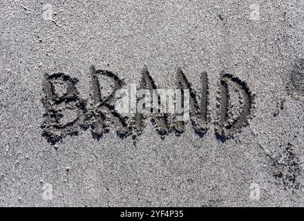 Konzept der Geschäftsmarke. Konzeptwort Marke geschrieben am wunderschönen Sandstrand des Meeres. Wunderschöner Ozean Sandstrand Hintergrund, Kopierraum. Geschäftsmarke Co Stockfoto