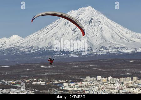 PETROPAVLOVSK-KAMTSCHATSKI, KAMTSCHATKA, RUSSLAND, 21. NOVEMBER 2014: Gleitschirmfliegen über Petropavlovsk-Kamtschatski-Stadt auf dem Hintergrund des aktiven K Stockfoto