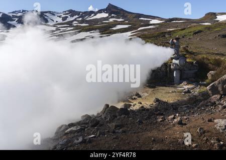 Emission von natürlichem Mineralthermalwasser, Dampf (Dampf-Wasser-Gemisch) aus geologischen Brunnen im geothermischen Ablagerungsgebiet, geothermischem Kraftwerk auf Steilhang Stockfoto