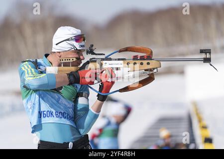 Sportlicher Biathlet, der Gewehrschießen im Stehen anstrebt. Kasachstan Biathlet Kireyev Vladislav im Schießstand Junior Biathlon Wettbewerbe Stockfoto