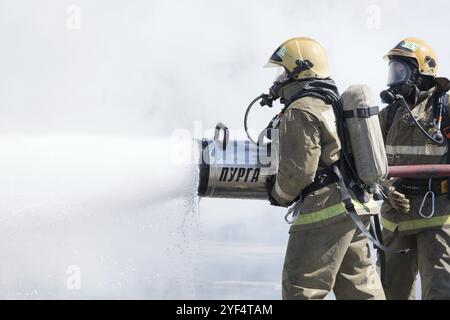 Zwei Feuerwehrleute löschen das Feuer aus dem Löschschlauch, mit der Brandbekämpfung Wasser-Schaum-Fass mit Luft-mechanischen Schaum während der professionellen Urlaub Feuerwehrmann Stockfoto