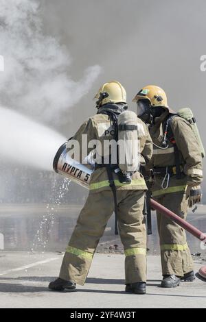 Die Feuerwehr löscht das Feuer aus dem Löschschlauch, indem sie Wasser-Schaumstofffass mit luftmechanischem Schaum verwendet. Professioneller Urlaub Feuerwehrmann Tag. P Stockfoto