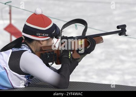 Sportsfrau Biathletin zielt, Gewehrschießen Bauchlage. Südkoreanischer Biathlet Yoonah Choi auf dem Schießstand. Junior Biathlon Wettkämpfe östlich von Stockfoto